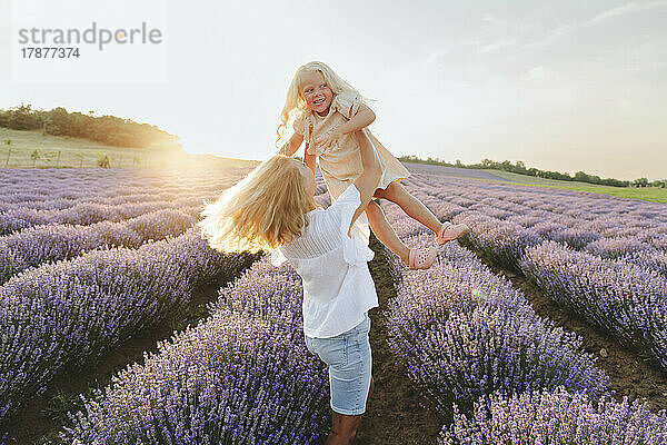 Verspielte Mutter genießt mit Tochter im Lavendelfeld