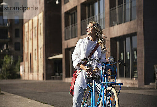 Lächelnde Frau  die auf dem Fahrrad sitzend das Sonnenlicht genießt