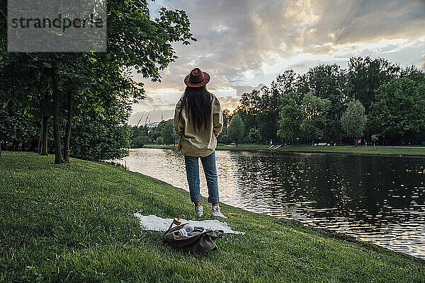 Frau steht und betrachtet den Sonnenuntergang im Park