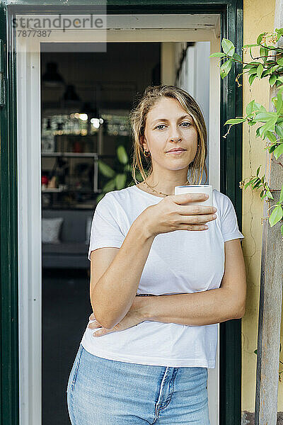 Selbstbewusste Geschäftsfrau mit Kaffeetasse vor der Tür