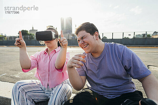Bruder lacht über Schwester mit Down-Syndrom  die einen Virtual-Reality-Simulator trägt