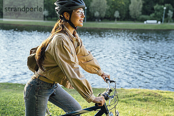 Frau fährt Fahrrad am See im Park