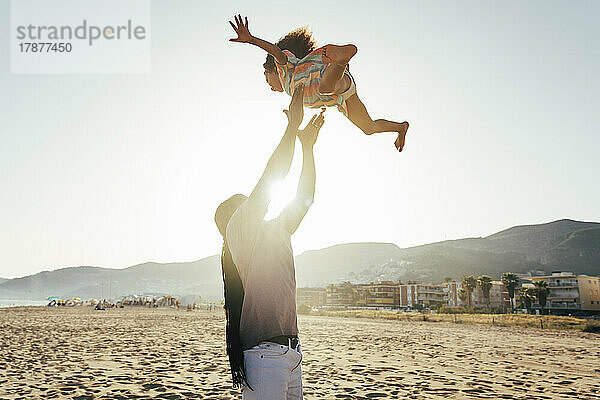 Verspielter Vater wirft Tochter am Strand in die Luft