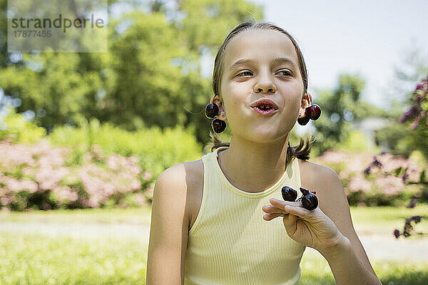 Nettes Mädchen  das Kirschen im Park isst