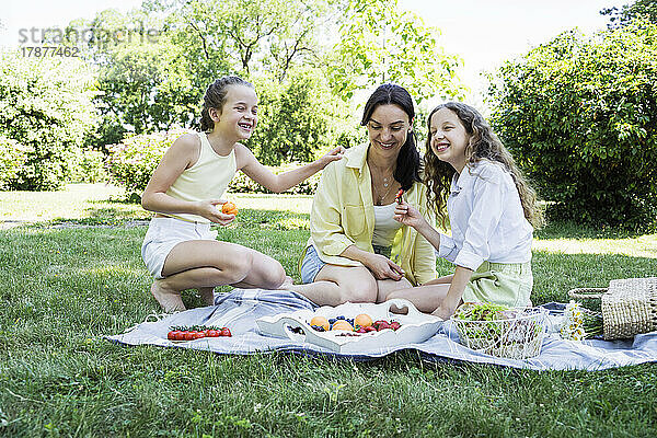 Glückliche Töchter  die am Wochenende mit ihrer Mutter ein Picknick im Park machen