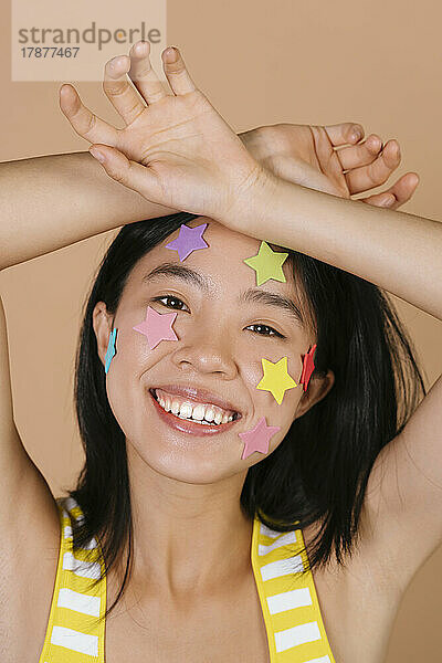 Glückliche junge Frau mit bunten Sternen im Gesicht