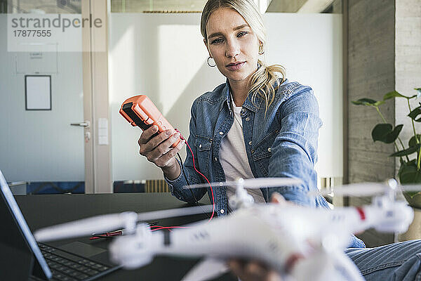 Frau misst die Spannung einer Drohne mit einem Multimeter im Büro