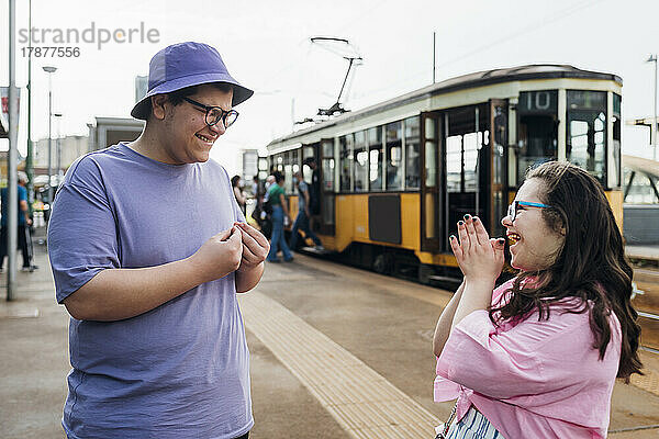 Glücklicher Bruder und Schwester lachen an der Straßenbahnhaltestelle in der Stadt