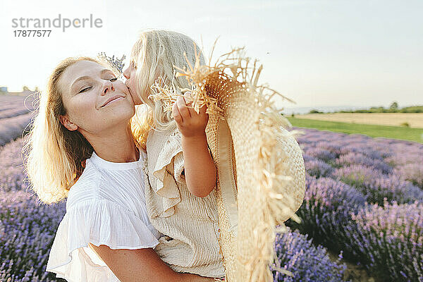 Mädchen mit Hut küsst Mutter am Lavendelfeld