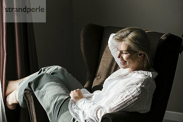 Happy woman relaxing in chair at home