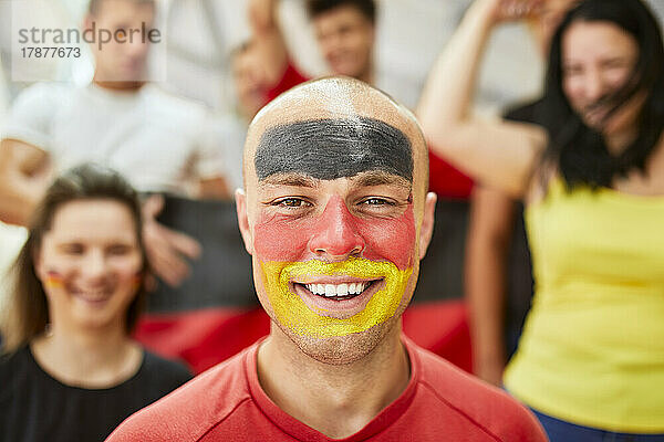 Glücklicher Mann mit deutscher Flagge im Gesicht im Stadion