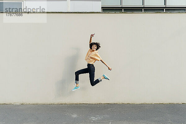 Fröhliche Frau springt vor die Wand