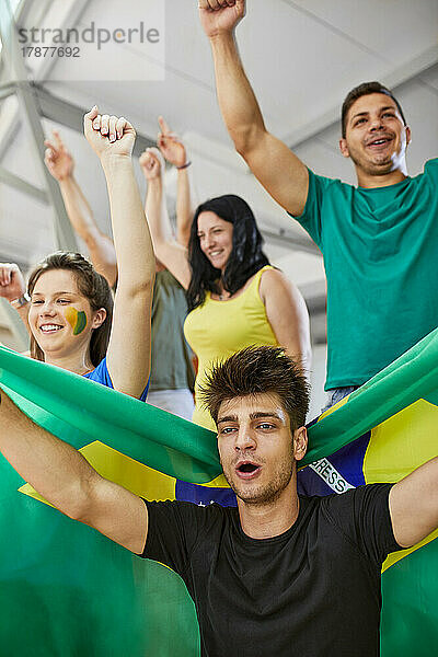 Begeisterte Fans mit Brasilien-Flagge jubeln gemeinsam bei Sportveranstaltung im Stadion