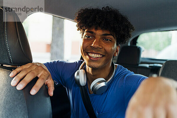 Lächelnder Mann mit lockigem Haar sitzt im Auto