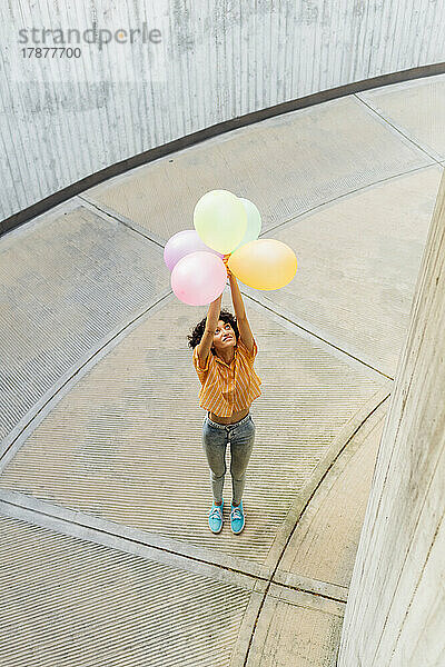 Frau mit Luftballons steht auf Fußweg