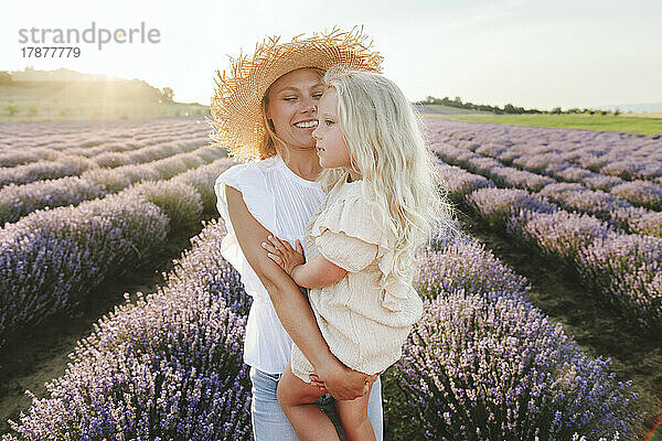 Lächelnde Frau mit Tochter steht im Lavendelfeld