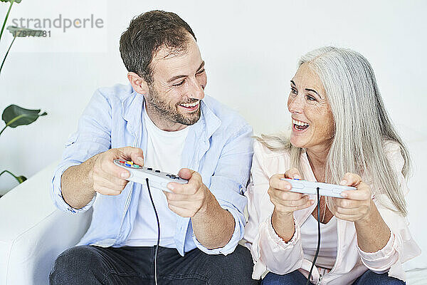Glückliche Mutter und Sohn spielen zu Hause Videospiele mit Controllern
