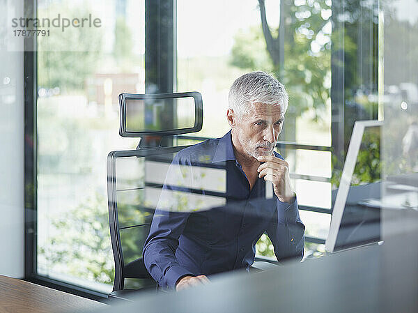 Reifer Geschäftsmann  der im Büro am Desktop-PC arbeitet