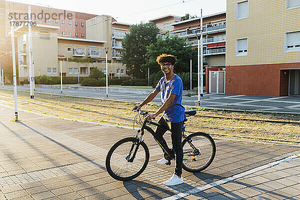 Lächelnder Mann mit Fahrrad auf der Stadtstraße