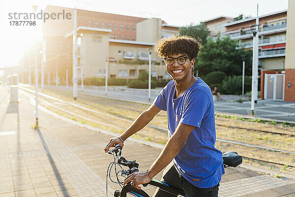 Glücklicher Mann mit Fahrrad steht in der Stadt