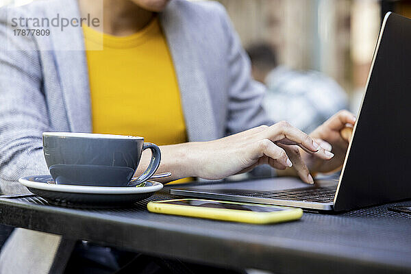 Hände einer Geschäftsfrau mit Laptop im Straßencafé