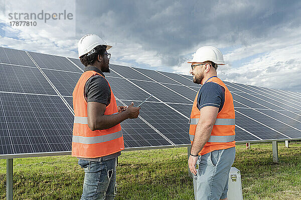 Gemischtrassige Ingenieure diskutieren an einer Solarstation