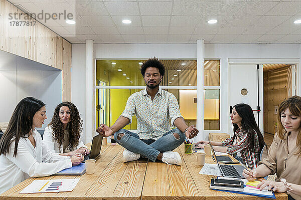 Geschäftsmann meditiert am Schreibtisch im Konferenzraum im Büro