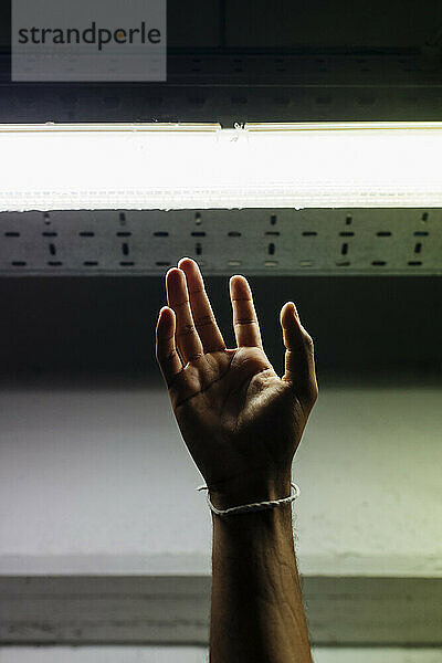 Hand eines Mannes  der in der U-Bahn nach LED-Licht greift