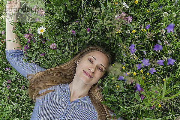 Happy mature woman lying on grass at field
