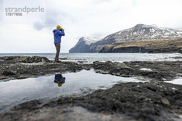 Färöer-Inseln  Eysturoy  Eidi  männlicher Wanderer fotografiert Küstenlandschaft