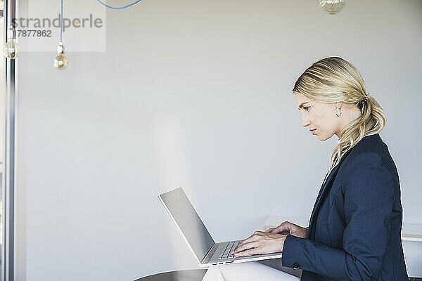 Blonde Geschäftsfrau benutzt Laptop im Büro