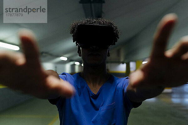 Junger Mann in Virtual-Reality-Kleidung gestikuliert mit den Händen in der U-Bahn