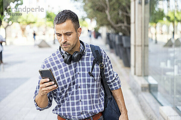 Reifer Mann benutzt Smartphone und geht auf Fußweg