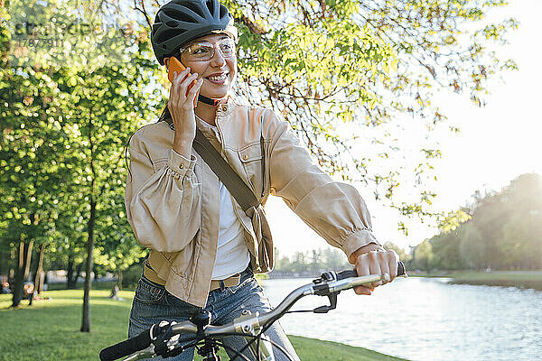 Lächelnde Frau  die mit dem Fahrrad auf dem Smartphone spricht