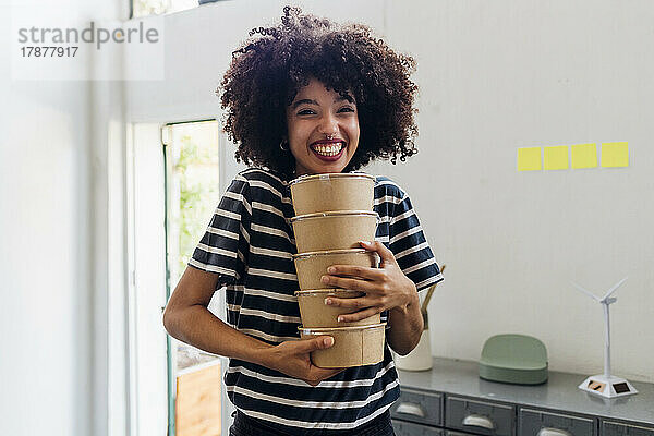 Glückliche Geschäftsfrau hält Lunchboxen im Büro