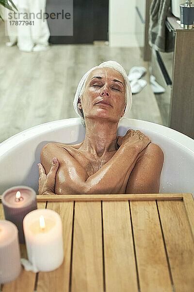 Mature woman taking bath and relaxing in bathroom