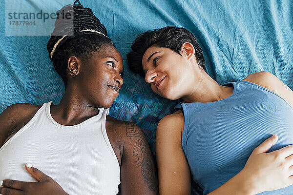 Lächelndes lesbisches Paar  das auf dem Bett liegt