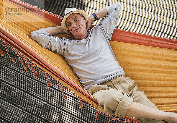 Man with hands behind head sleeping in hammock