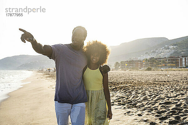 Vater geht mit Tochter spazieren und zeigt auf den Strand