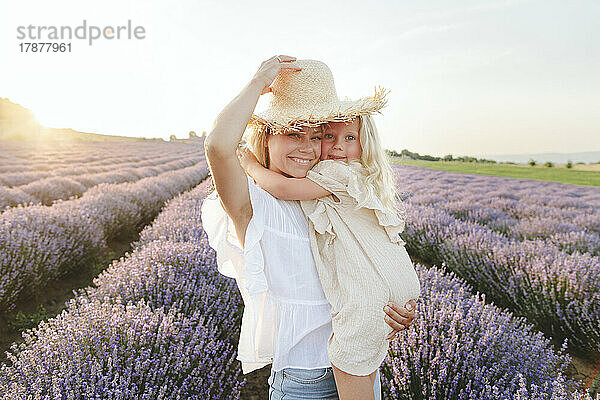 Nettes Mädchen mit Mutter mit Hut steht im Lavendelfeld