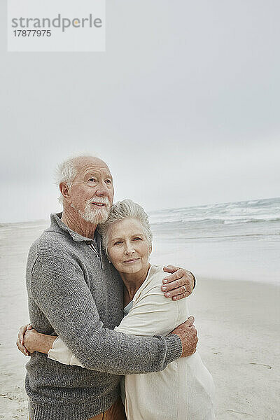 Älteres Paar umarmt sich am Meer