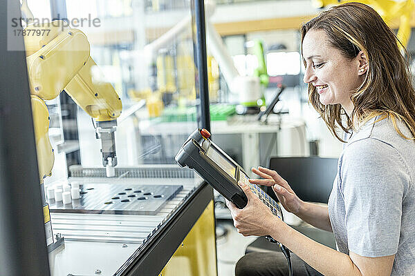 Frau in der Fabrik nutzt die Steuerung eines Industrieroboters