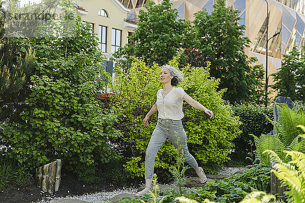 Carefree woman running by plants in park