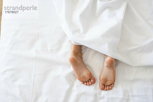 Girl lying in bed with bare feet