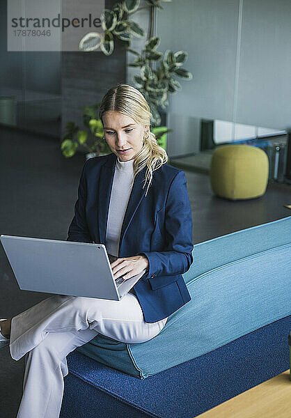 Geschäftsfrau sitzt mit Laptop auf der Couch im Büro