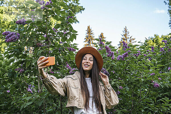 Lächelnde Frau  die im Park ein Selfie mit dem Handy macht