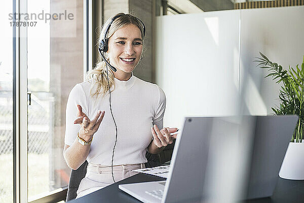 Kundendienstmitarbeiter gestikuliert bei Videoanruf über Laptop im Büro