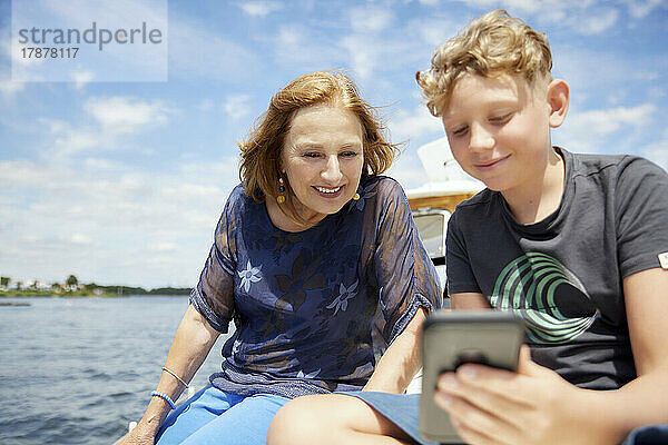 Junge teilt Smartphone mit Großmutter auf Boot