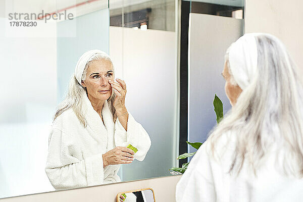 Beautiful woman applying face cream