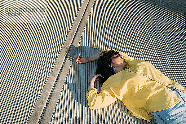 Woman lying on footpath at sunny day